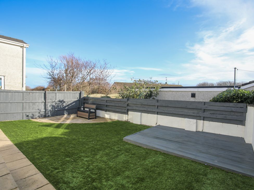 A garden with grass and a wooden deck at Penrhos Walks in Holyhead