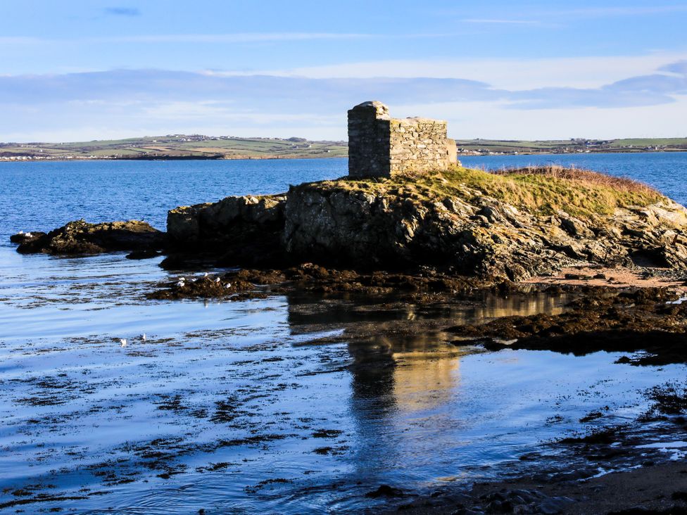 A rocky outcrop with a building on top surrounded by water at Penrhos Walks in Holyhead