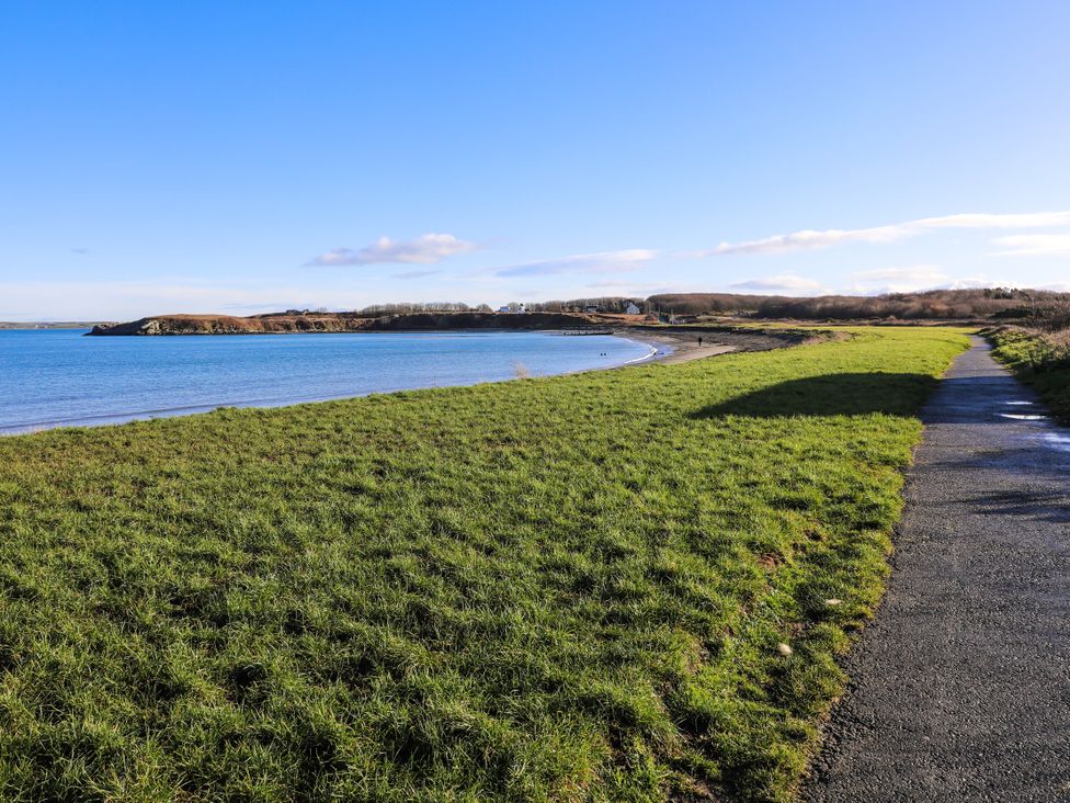 A pathway along the shore with grass and water at Penrhos Walks Holyhead