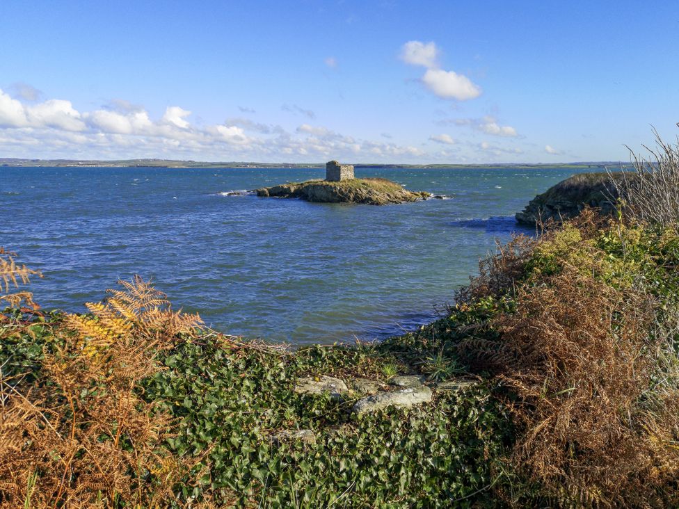 A coastal view with an island and a stone structure at Penrhos Walks Holyhead