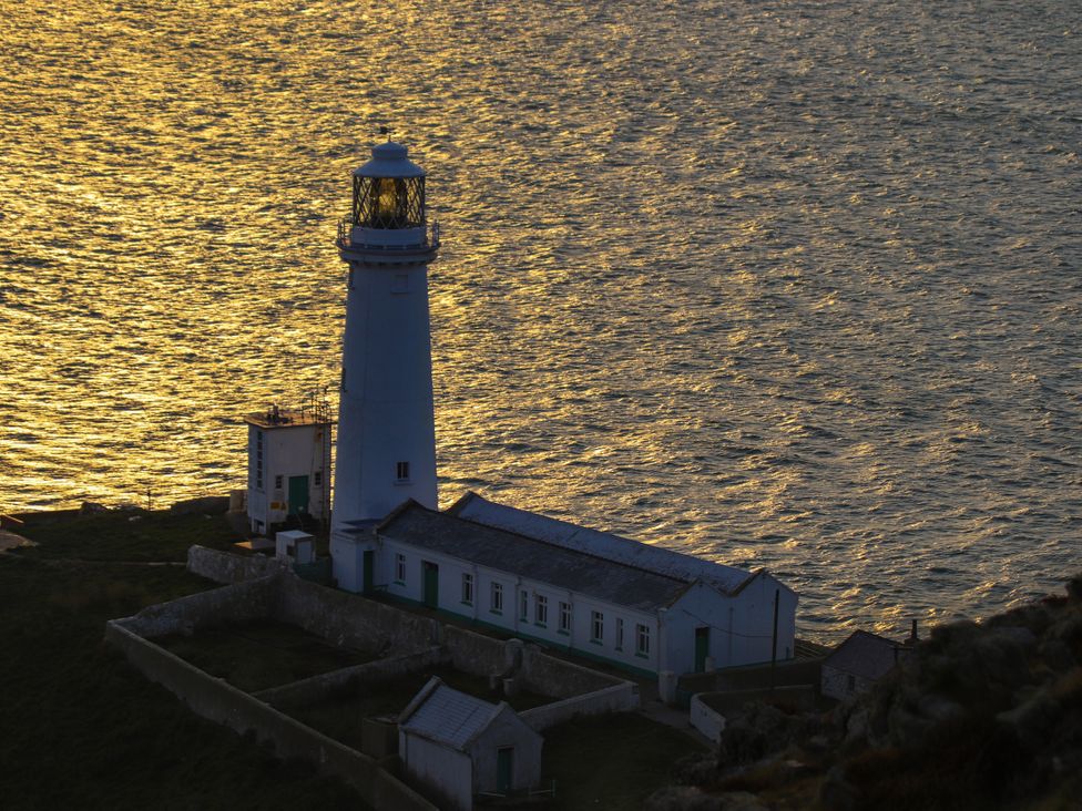 A lighthouse beside water at Penrhos Walks in Holyhead