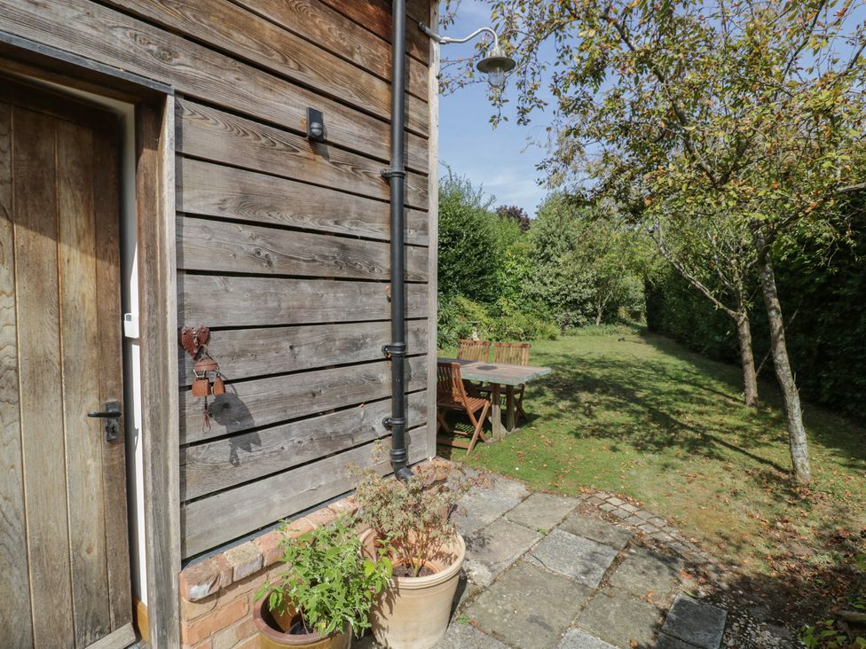 A garden with a wooden table and chairs at The Shed in Stratford-upon-Avon