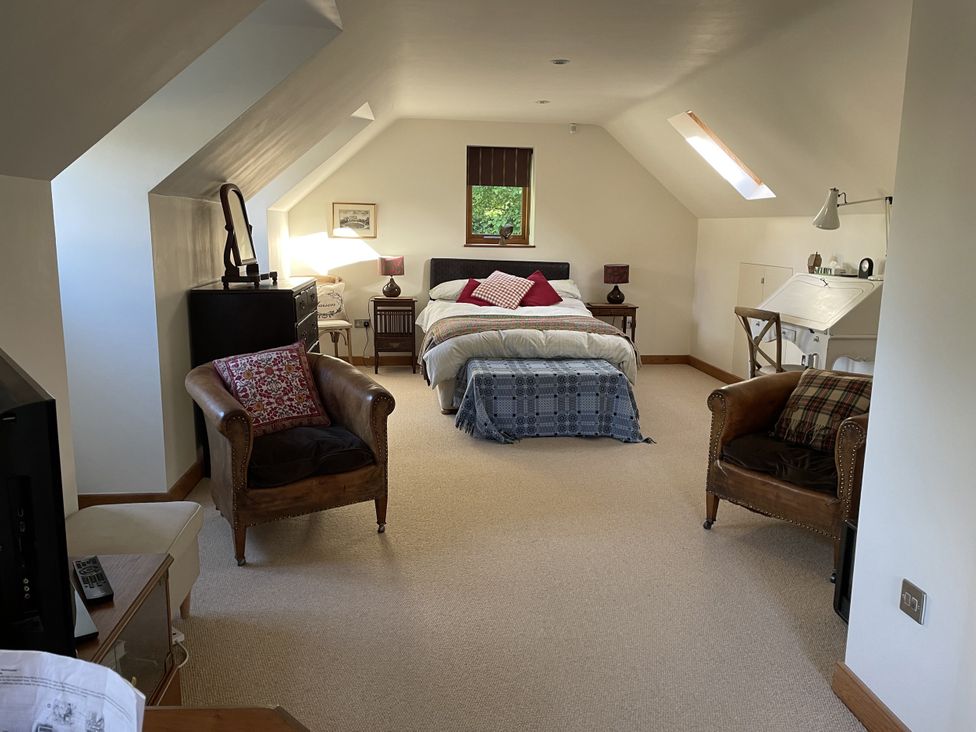 A bedroom with a bed and armchairs at The Shed in Alveston near Tiddington