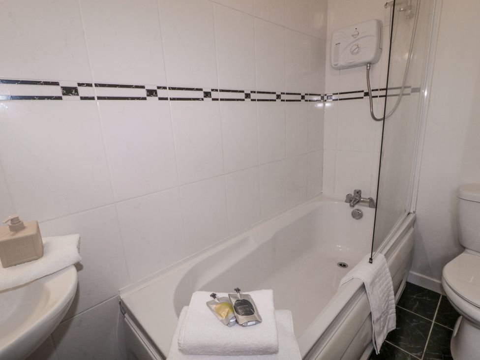 A bathroom with a bathtub, toilet, sink, and bath products at Burna in Letterkenny