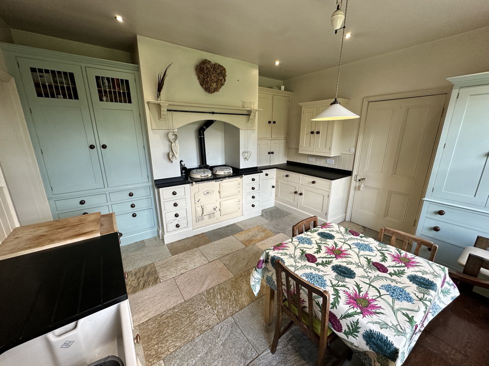 A kitchen with cabinets, a sink, and a table in The Old Vicarage 