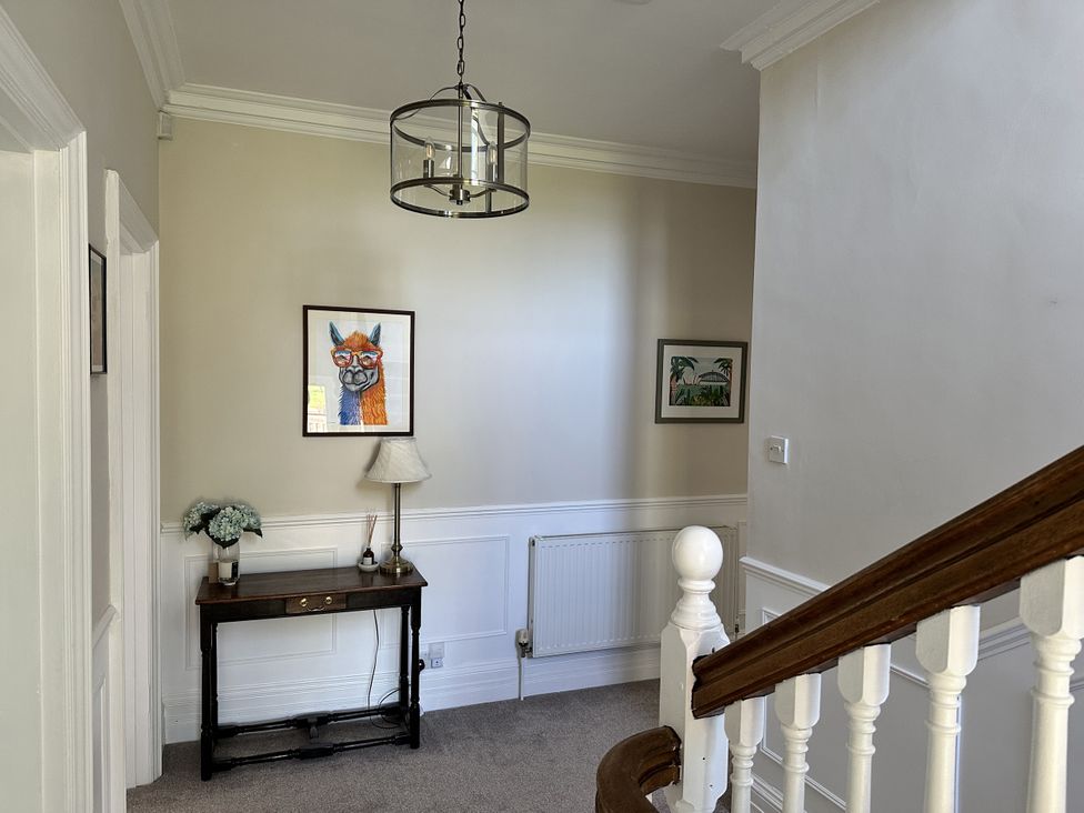 A hallway with a staircase and wall art at The Old Vicarage 