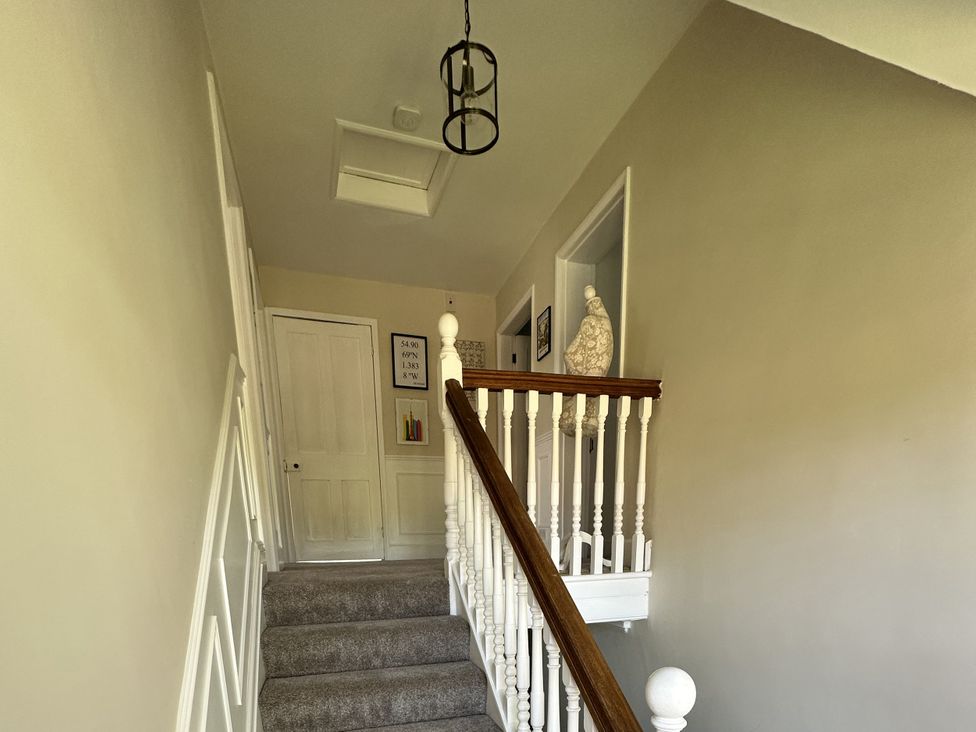 A staircase and landing area with a door and framed artwork at The Old Vicarage