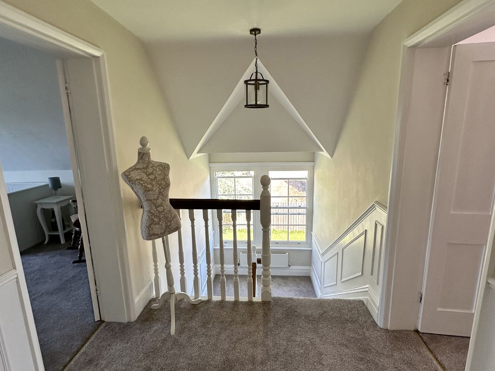 A hallway with a staircase and mannequin at The Old Vicarage in 
