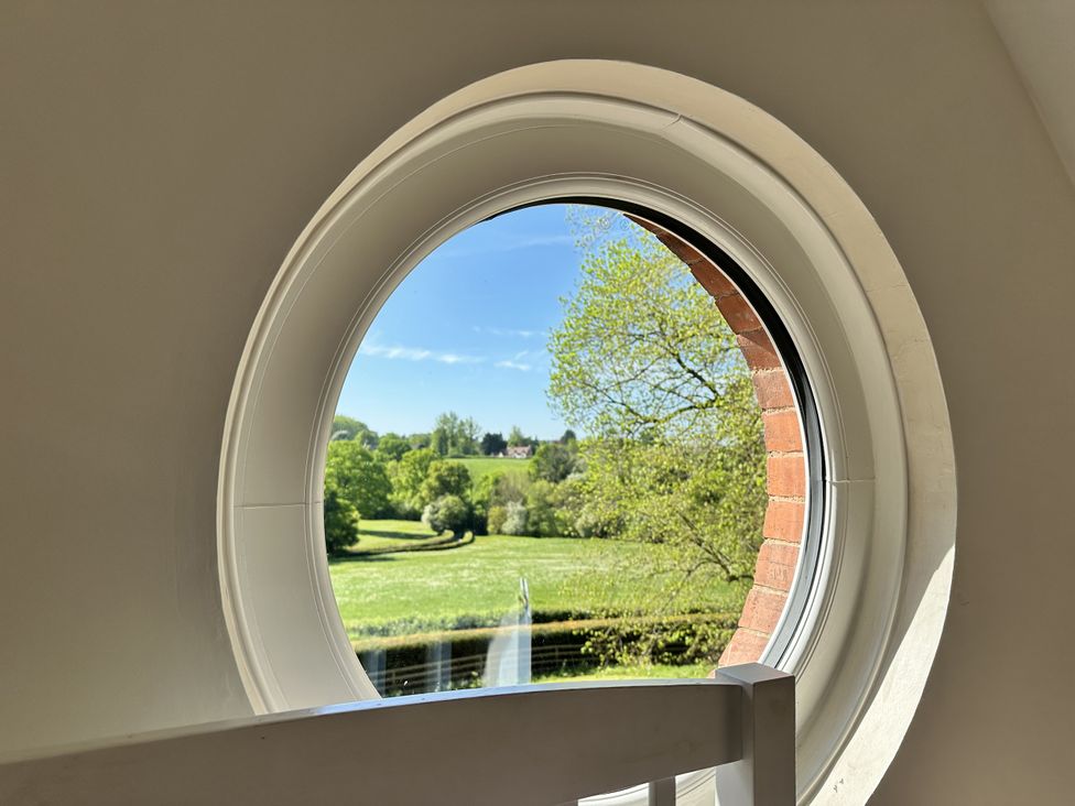 A view of trees and grass through a circular window at The Old Vicarage