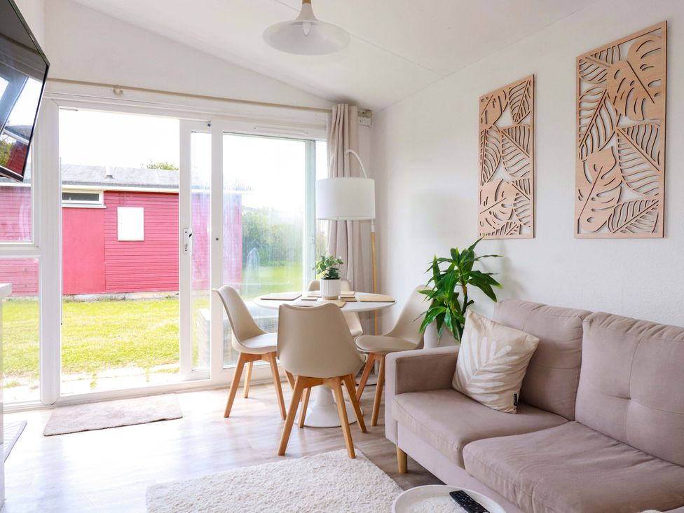 A living room with a sofa and dining area at Cozy Retreat in Tregolds