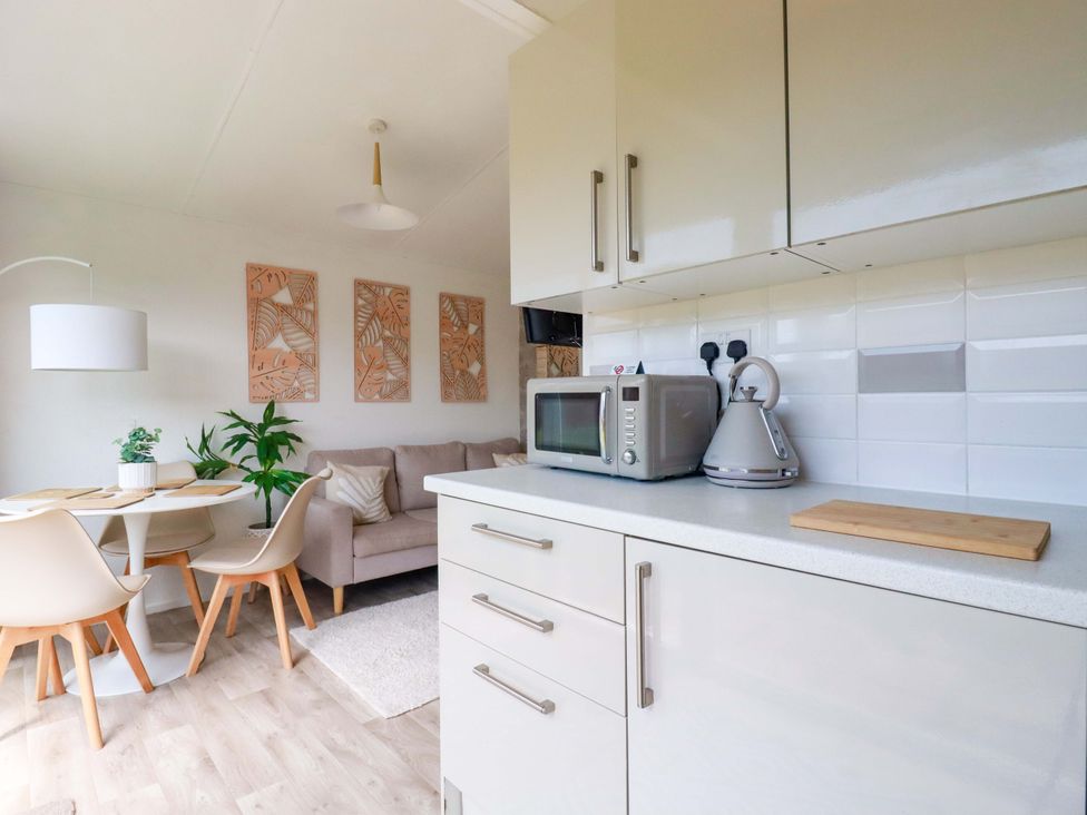 A kitchen with a microwave kettle and table with chairs at Cozy Retreat in Tregolds