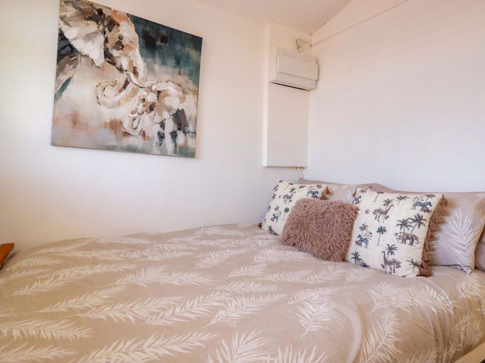 A bedroom with a bed and artwork on the wall at Cozy Retreat in Tregolds