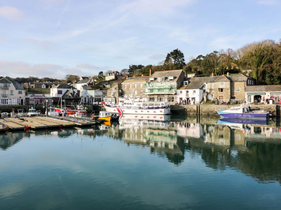 A harbor with boats and buildings reflected in the water at Cozy Retreat in Tregolds