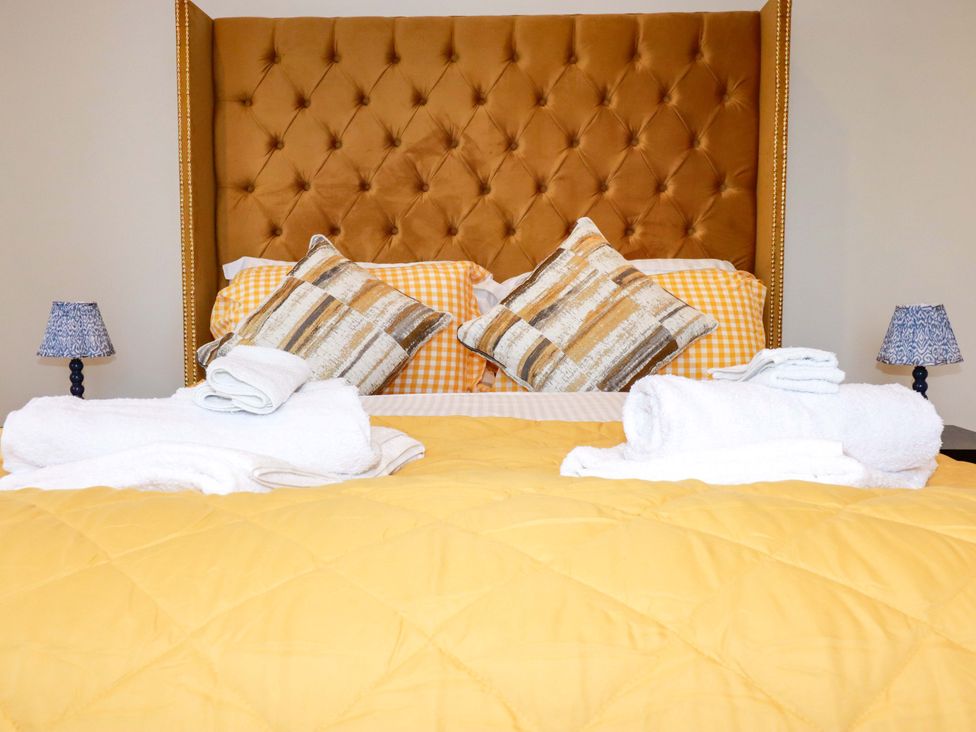 A bedroom with a yellow bedspread and pillows at Ocean Edge in Sennen Cove