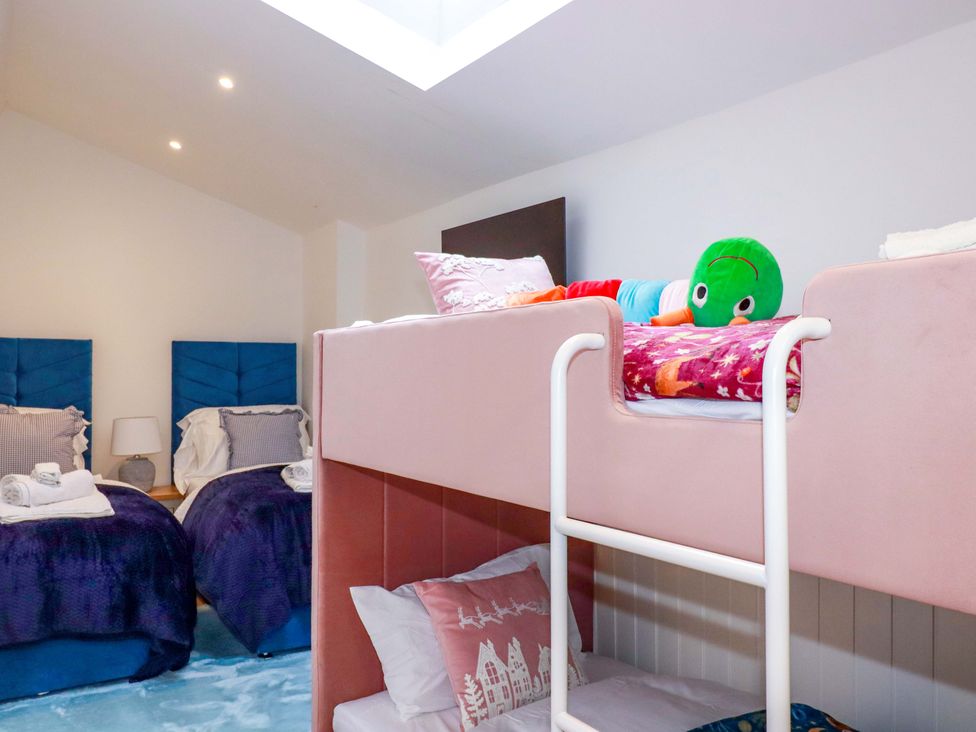 A bunk bed and twin beds in a bedroom at Ocean Edge in Sennen Cove