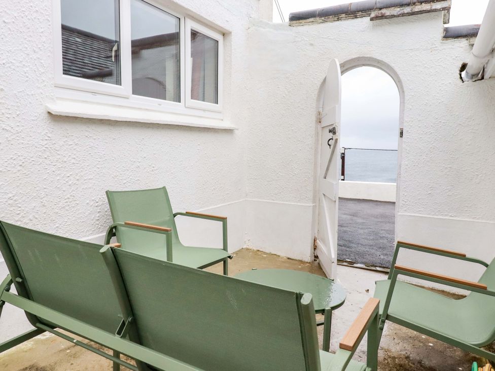 An outdoor area with green chairs and a table at Ocean Edge in Sennen Cove