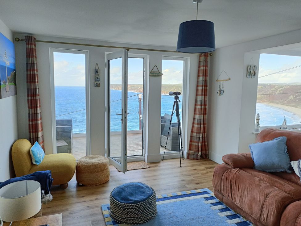 A living room with a telescope and sofa at Ocean Edge in Sennen Cove