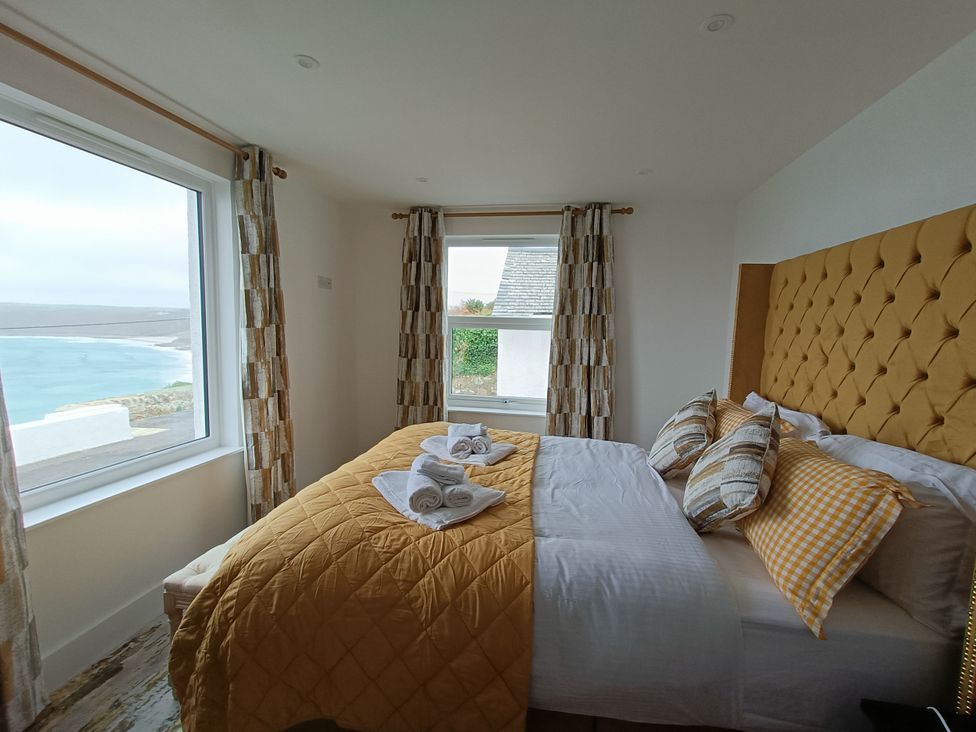 A bedroom with a bed and views of the ocean at Ocean Edge in Sennen Cove