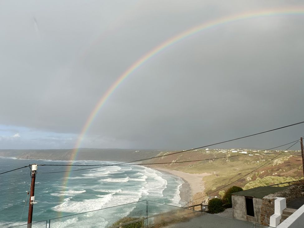A view of a rainbow over the ocean and coastline at Ocean Edge in Sennen Cove