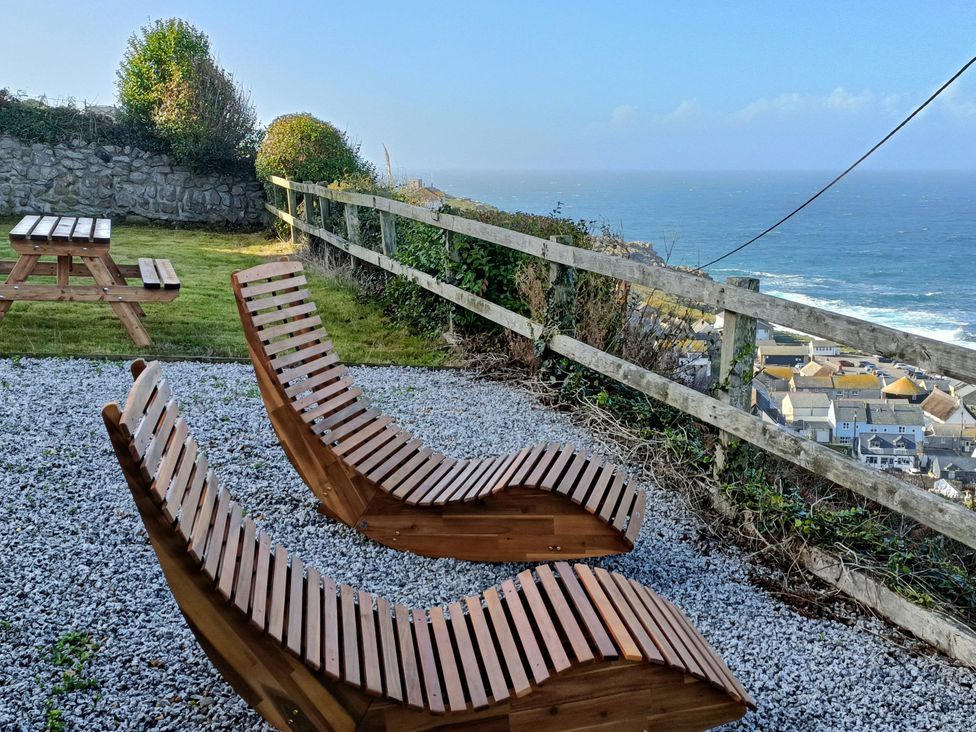 An outdoor area with wooden loungers and a picnic table at Ocean Edge in Sennen Cove