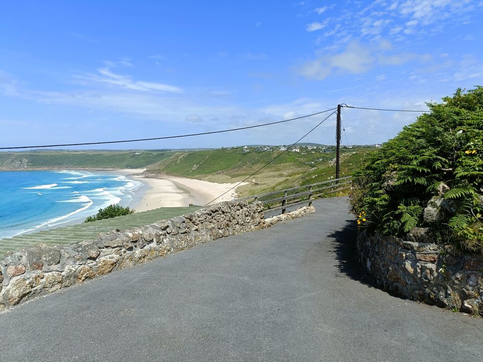 A view of a beach and ocean with a road leading to it at Ocean Edge Sennen Cove