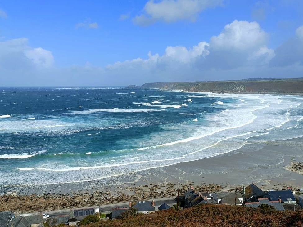 A view of waves and beach with houses at Ocean Edge in Sennen Cove