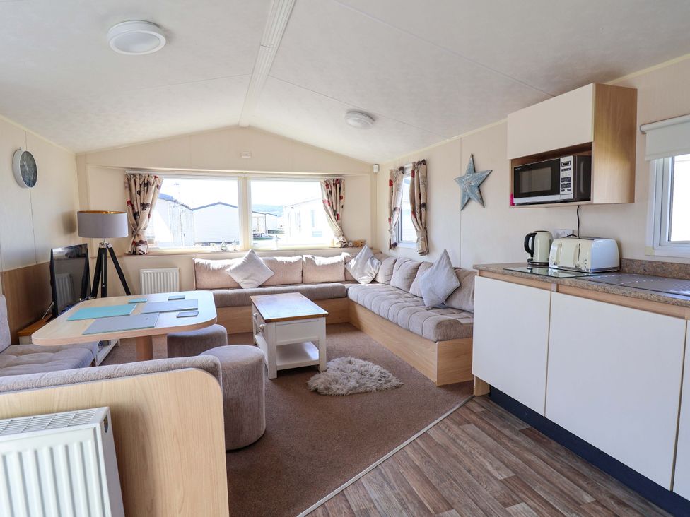 A living room with a sofa and dining table at Willerby Aurora B14 in Towyn