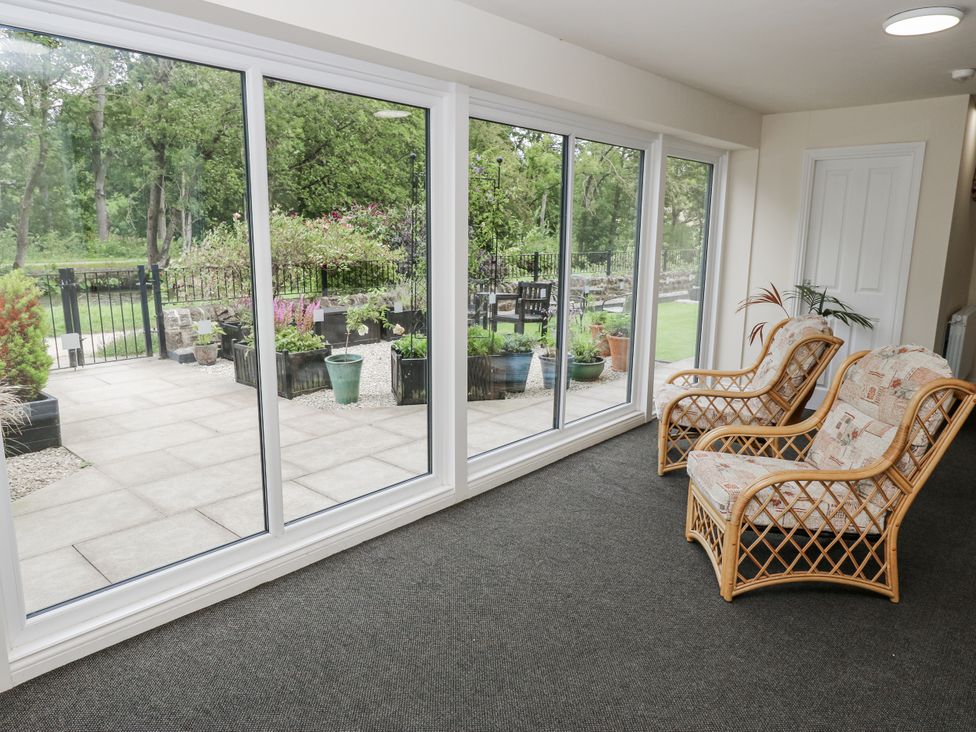 A conservatory with glass windows and chairs at Apartment 5 in Skipton