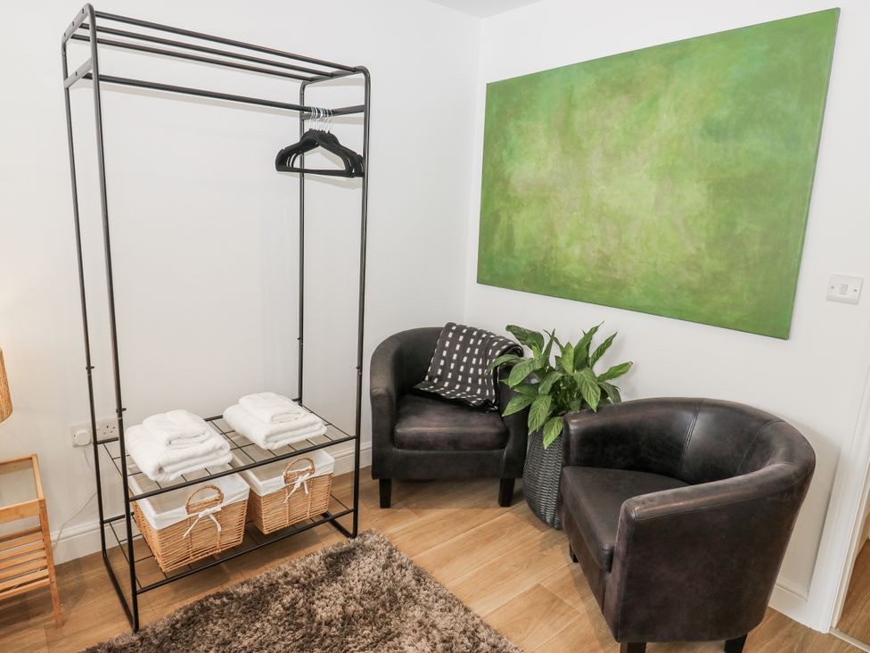 A living room with a clothing rack and armchairs at Apartment 5 Skipton