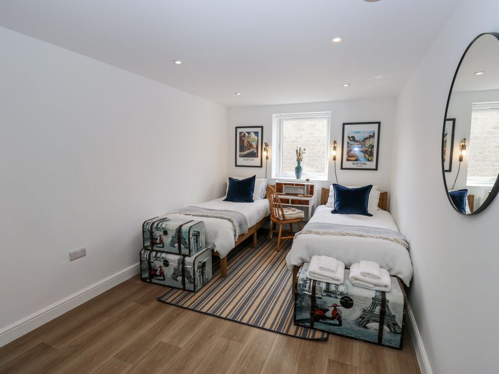A bedroom with two beds and a table at Apartment 5 in Skipton