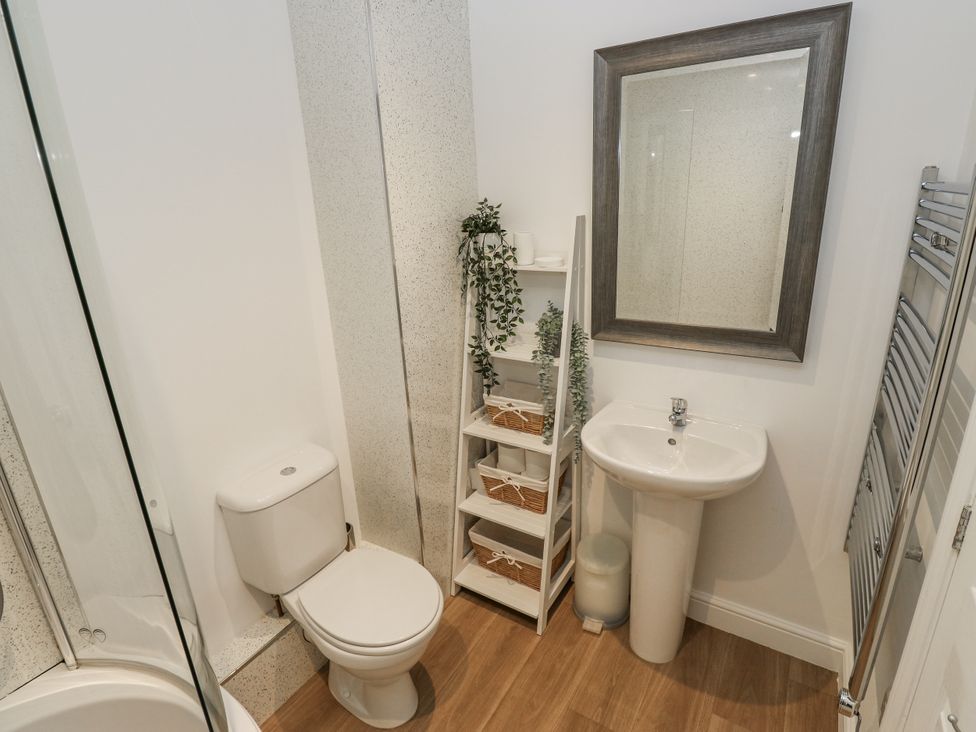 A bathroom with a toilet, sink, and shelves at Apartment 5 in Skipton