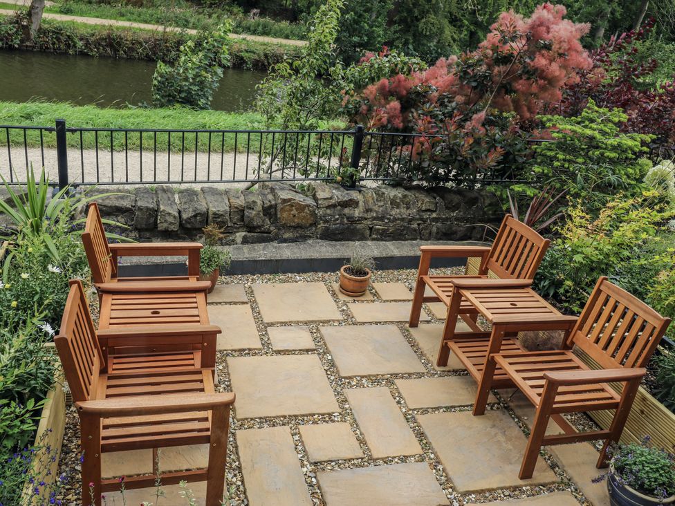 An outdoor patio with wooden chairs and a potted plant at Apartment 5 in Skipton