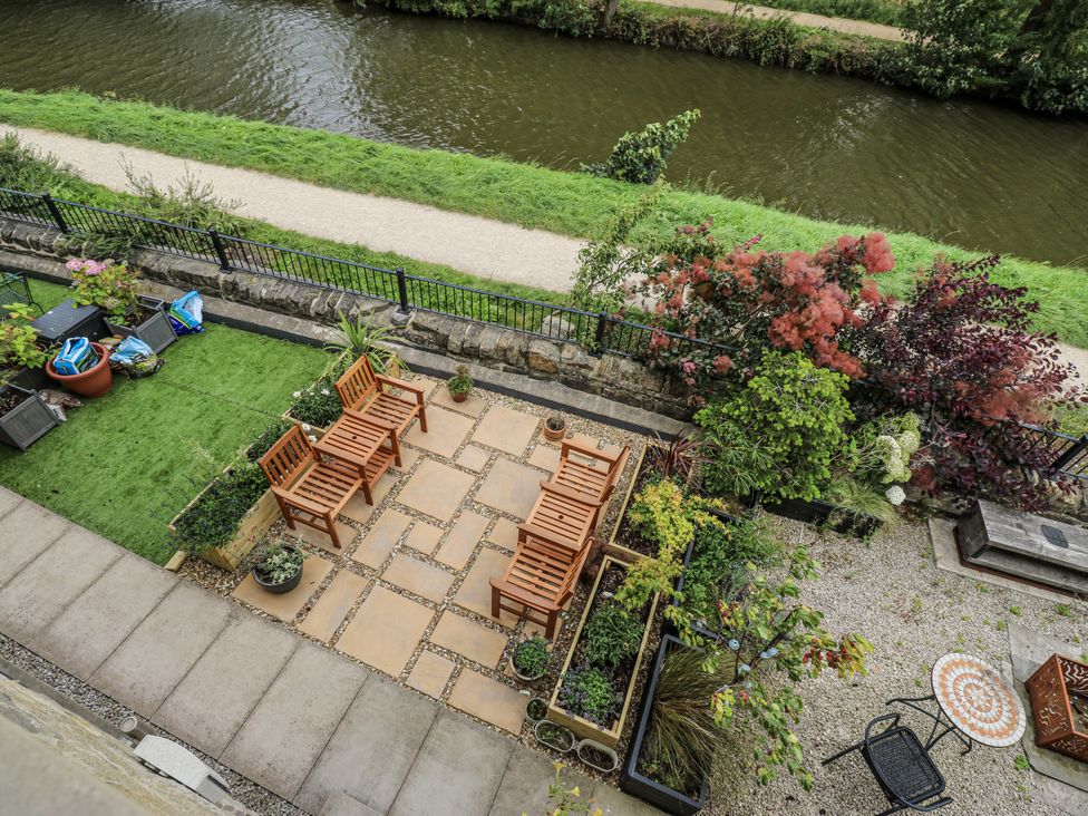 A garden with chairs and planters near a canal at Apartment 5 Skipton