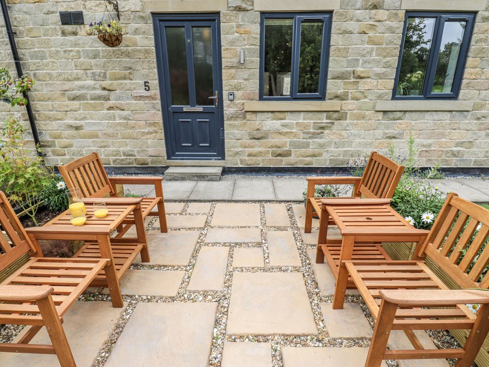 An outdoor seating area with four chairs and a table at Apartment 5, Skipton