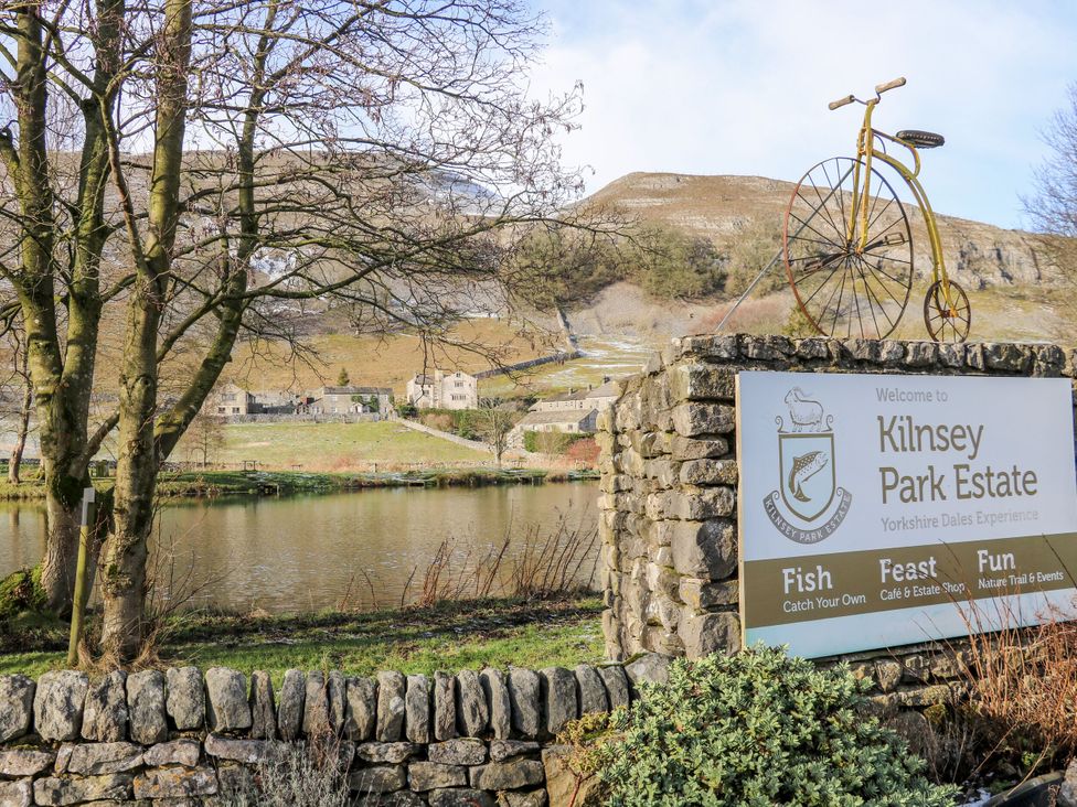 A sign for Kilnsey Park Estate with a bicycle and lake in the background at Kilnsey Park Estate in Skipton