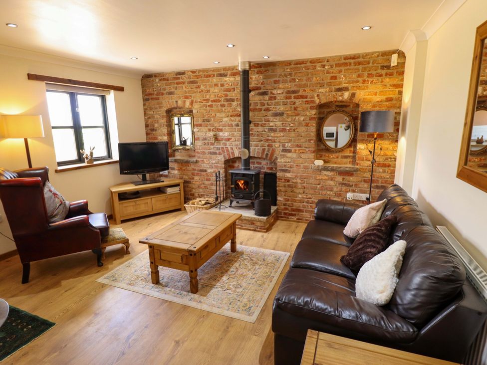 A living room with a sofa, coffee table, and television at The Paw Barn in Scrane End near Boston