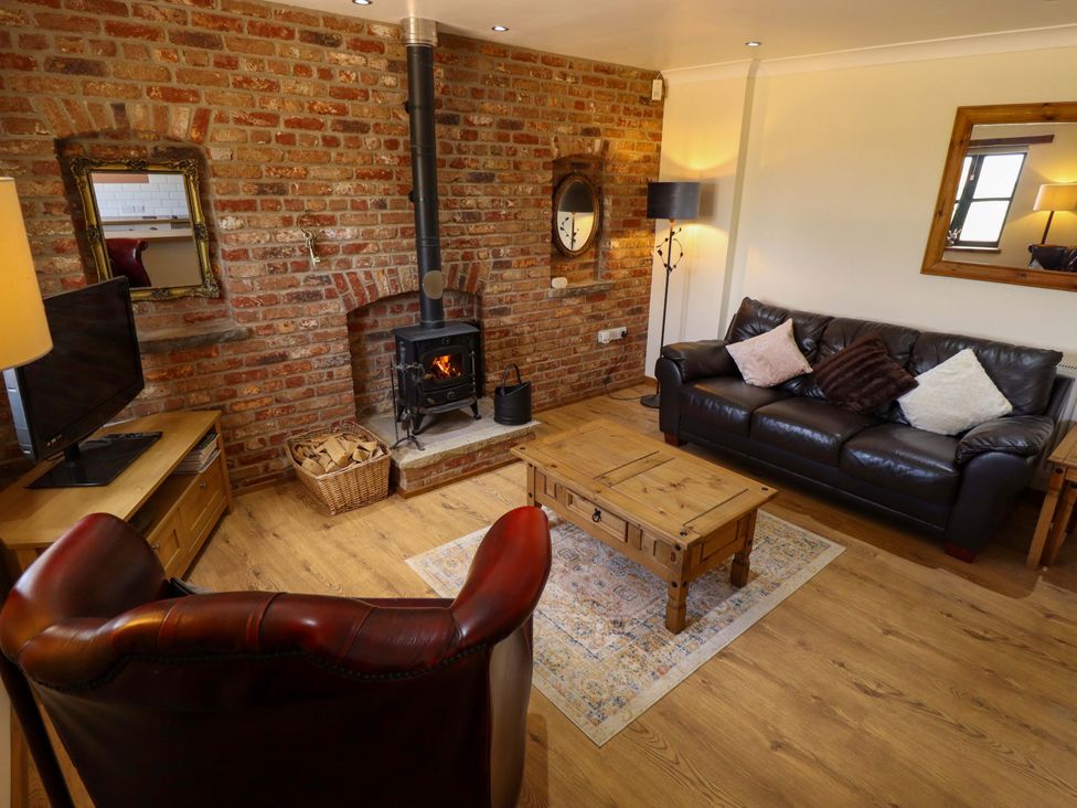 A living room with a fireplace and seating area at The Paw Barn in Scrane End near Boston