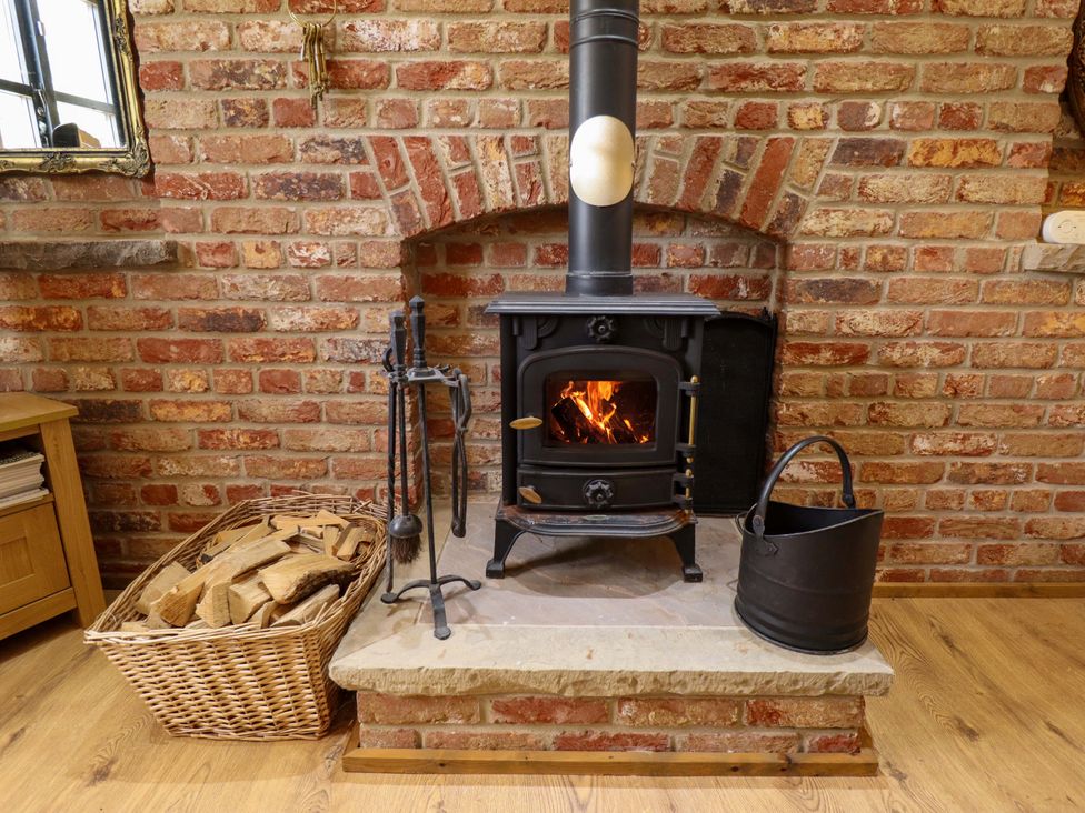 A living room with a wood stove and firewood basket at The Paw Barn Scrane End near Boston