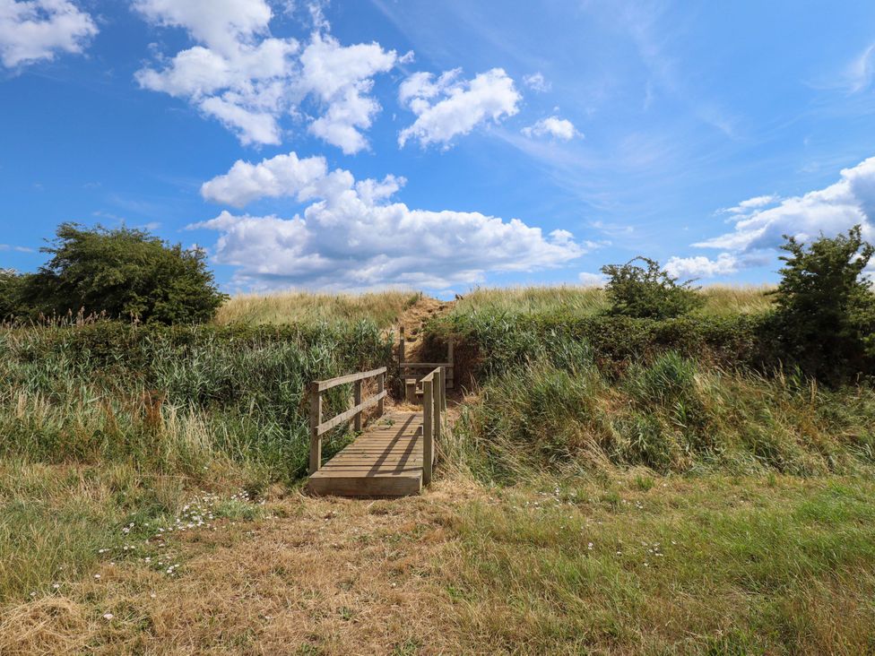 A wooden bridge leading to a pathway surrounded by grass at The Paw Barn Scrane End near Boston