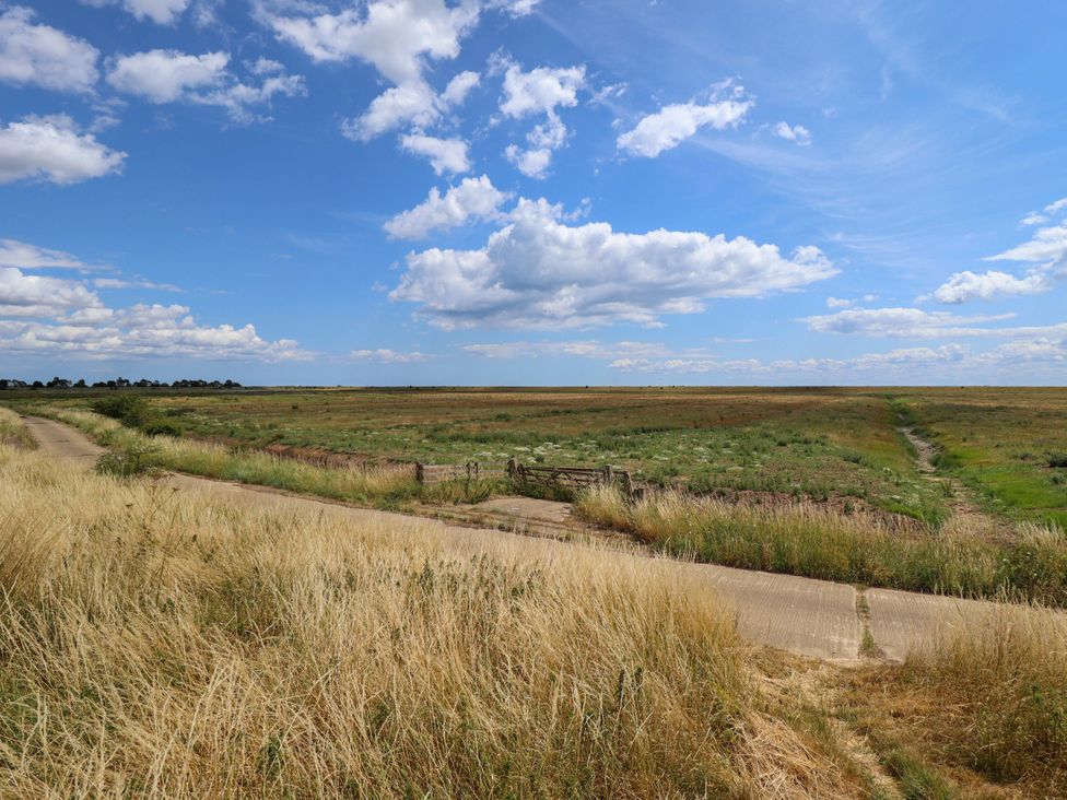 A road leading to a gate in a grassy field at The Paw Barn Scrane End near Boston