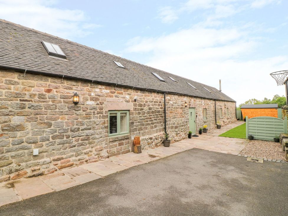 An outdoor area with a stone building and landscaped garden at The Barn in Wirksworth