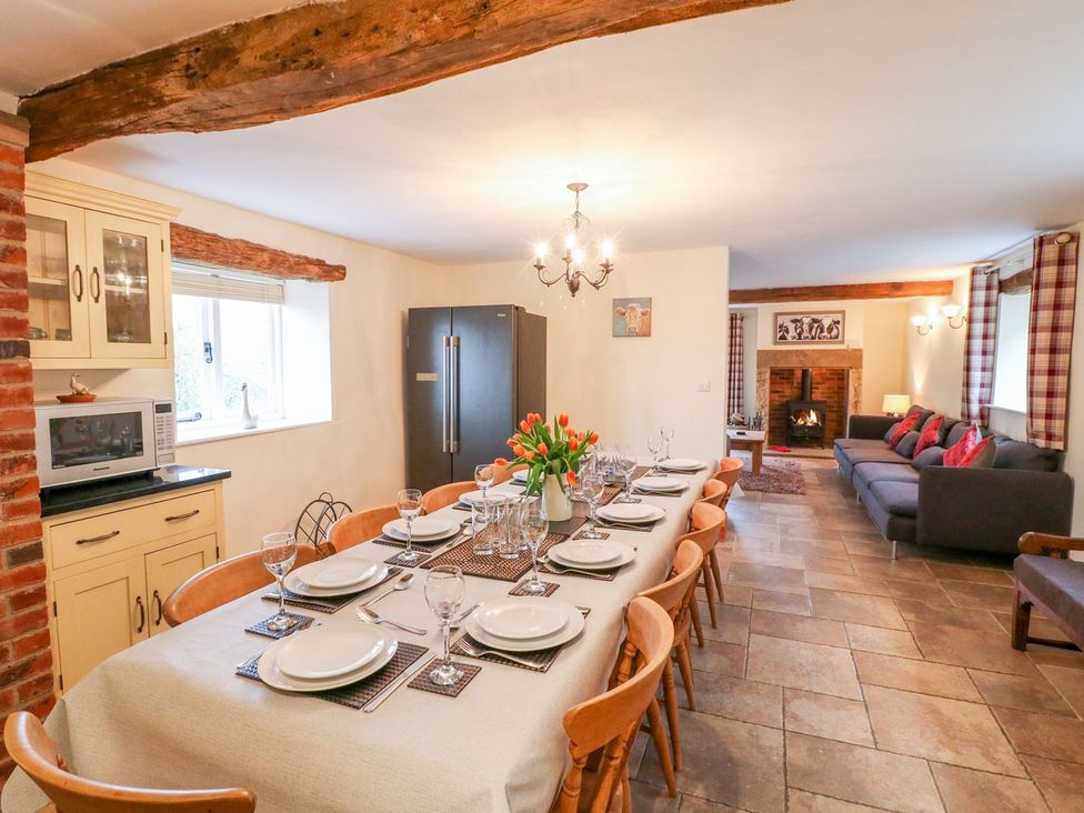 A dining room with a long table and fireplace at The Barn in Wirksworth