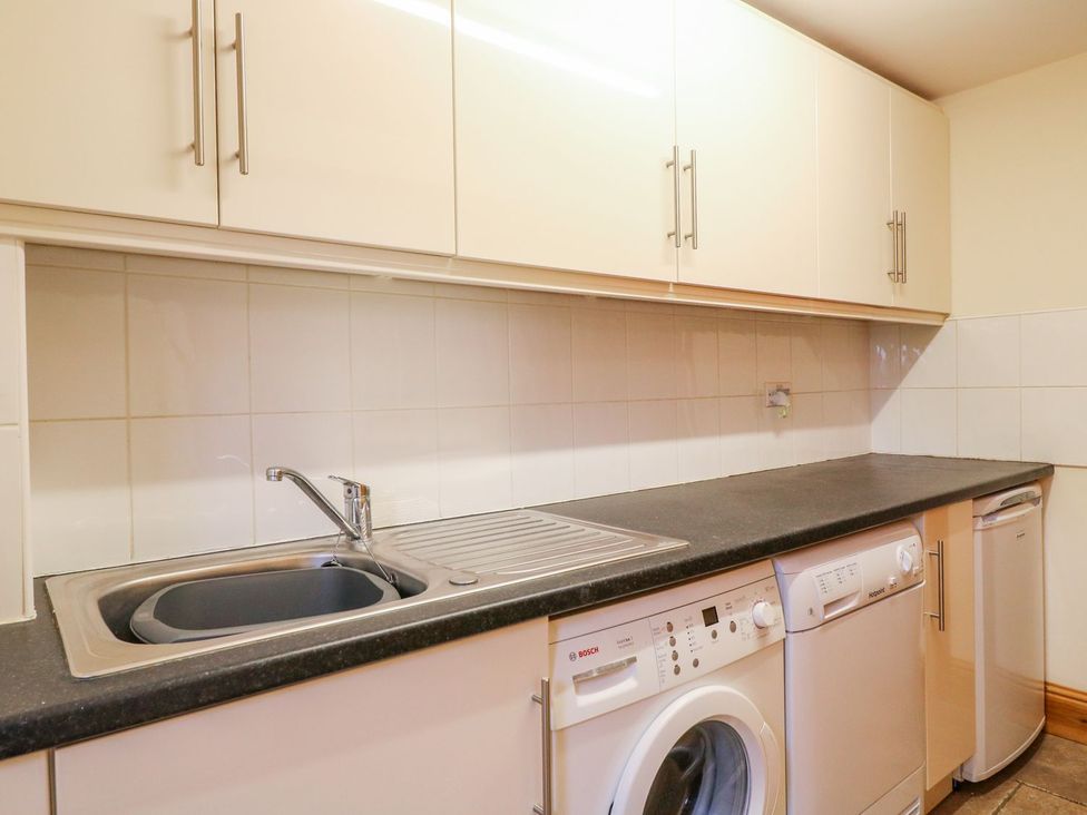 A laundry room with a sink, washing machine and dishwasher at The Barn in Wirksworth