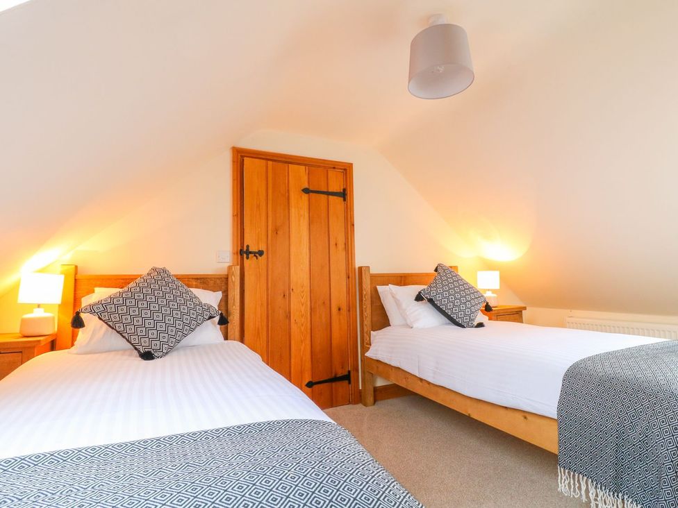 A bedroom with two beds and wooden furniture at The Barn in Wirksworth