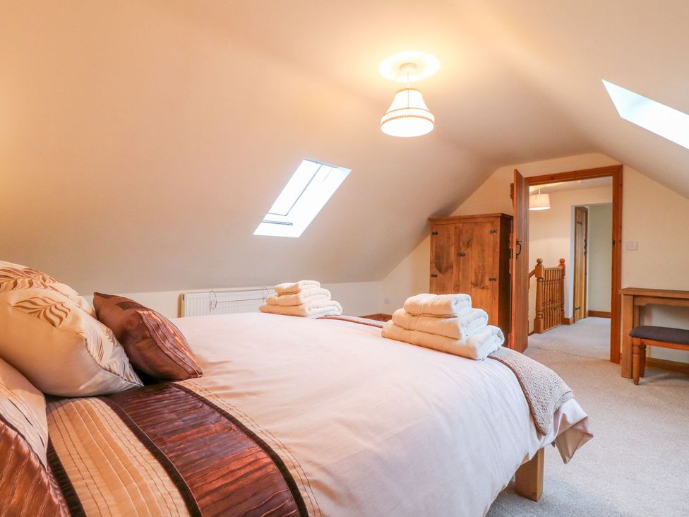 A bedroom with a bed and wardrobe at The Barn in Wirksworth