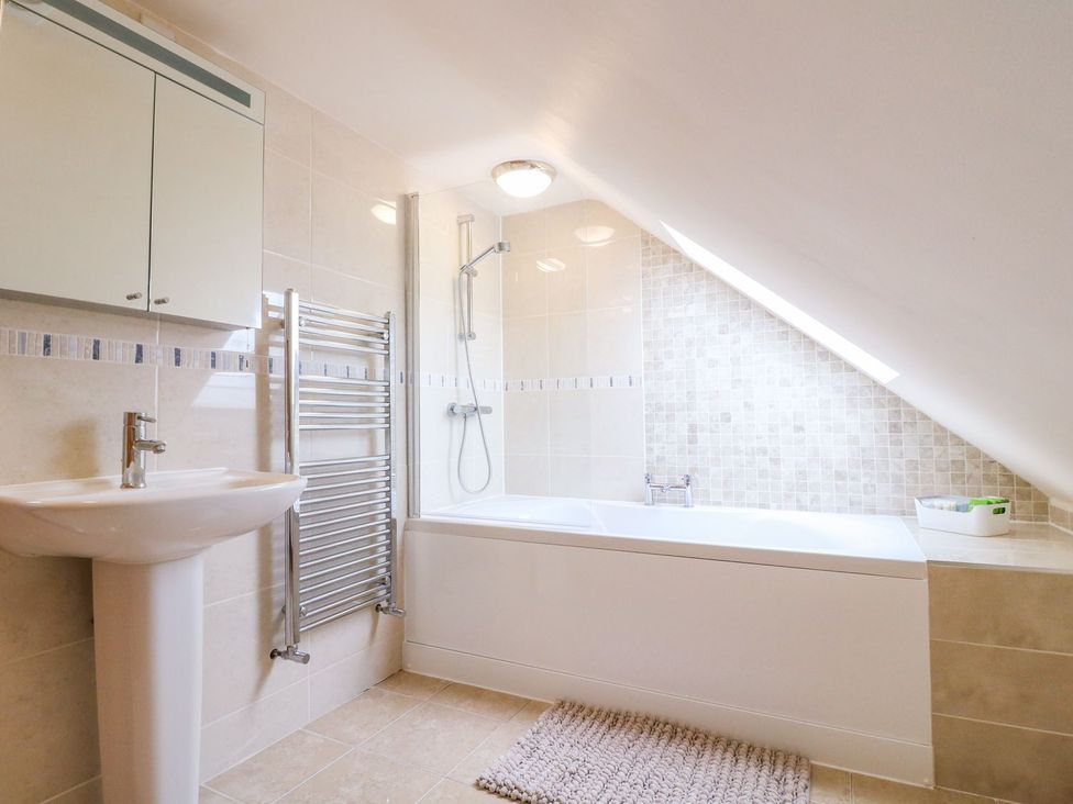 A bathroom with a bathtub, sink, and towel radiator at The Barn in Wirksworth