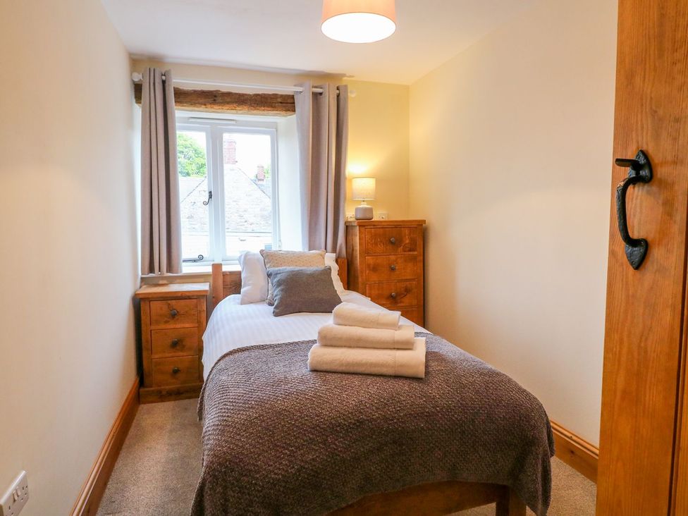 A bedroom with a bed, chest of drawers and window at The Barn in Wirksworth