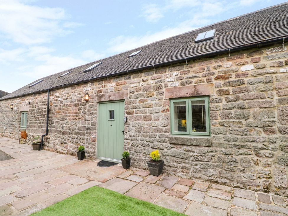 An exterior view of a stone building with a green door and planters at The Barn in Wirksworth