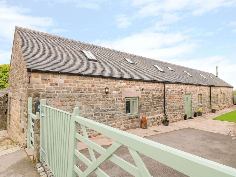 An exterior view of a stone house with a green gate at The Barn in Wirksworth
