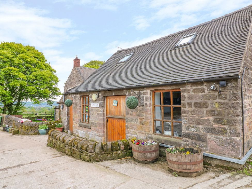A stone house with wooden door and flower pots at The Barn in Wirksworth
